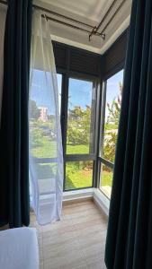 a bedroom with a large window with a white curtain at Pearl Escape in Entebbe