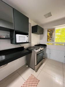 a kitchen with a stove and a microwave at Prédio Solar do Atlântico, apt 204 - Apartamento lateral em Tambaú in João Pessoa
