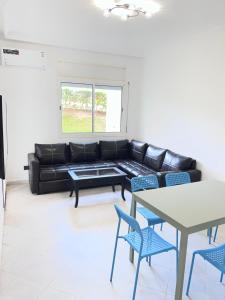 a living room with a black leather couch and blue chairs at Apparemment marina smir in Marina Smir