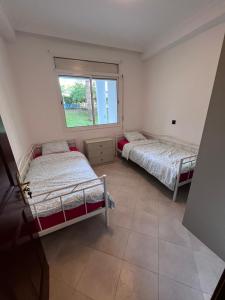 two beds in a room with a window at Apparemment marina smir in Marina Smir