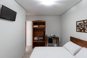 a bedroom with two beds and a desk and a television at Romas Hotel in Umuarama