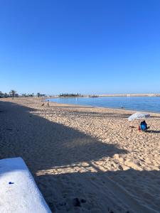 a beach with two people sitting under an umbrella at Apparemment marina smir in Marina Smir