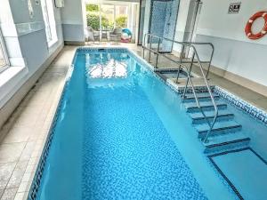 a swimming pool with blue water and stairs in a house at Brompton Lodge in Ganton