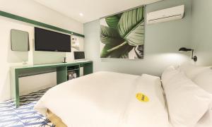 a bedroom with a bed and a desk with a television at Hotel Yeogiuhtte Chungjangro in Gwangju +3 photos