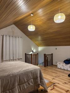 a bedroom with a bed and wooden ceiling with two lights at Chalé Recanto da Grota in Passa Vinte