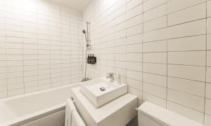 a white bathroom with a sink and a bath tub at Hotel Yeogiuhtte Chungjangro in Gwangju