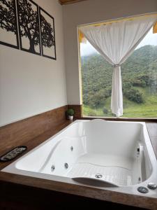a bath tub in a bathroom with a window at Chalé Recanto da Grota in Passa Vinte +44 photos