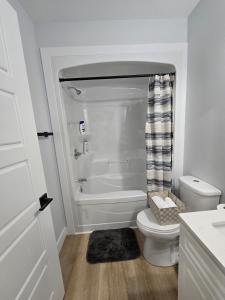 a white bathroom with a toilet and a tub at Serene luxury apartment in Moncton