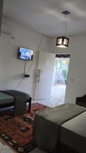 a room with two beds and a tv on the wall at Hospedaria Rancho Pérola in Guanambi
