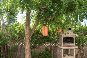 a tree with two orange lanterns and a stone oven at Le Cocon Méditerranéen - Plage à 5 min - Place de Parking - Barbecue - Terrasse in Le Barcarès