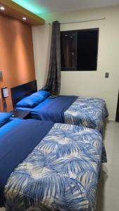 two beds in a hotel room with blue sheets at hotel del valle in Coatzacoalcos +16 photos