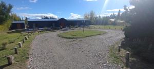 a gravel road leading to a building in a field at Hostería Ayres del Lago in Los Antiguos
