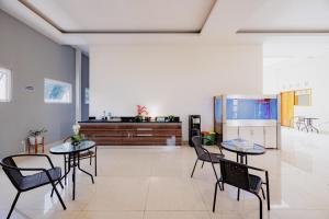 a living room with two tables and chairs and a kitchen at Urbanview Darmo Residence Bandung in Bandung