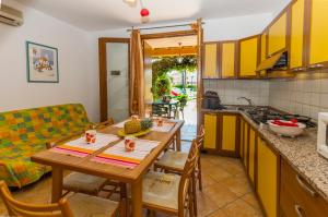 cocina y comedor con mesa de madera y sillas en Residence Borgo Stella Marina, en Bibione