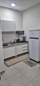 a kitchen with white cabinets and a refrigerator at Studio Central in Campo Grande