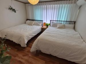 two beds sitting next to a window in a bedroom at 스미다 stay in Bucheon +5 photos