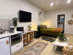 a living room with a bed and a tv on the wall at Shady Lane - Wallagoot in Jellat Jellat