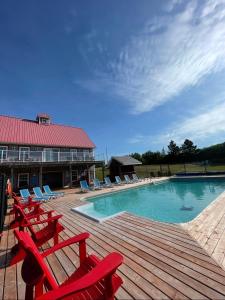 a swimming pool with red chairs and a wooden deck at Home Away From Home in Stanley Bridge