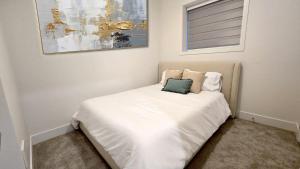 a small bed with white sheets and a green pillow at Mountain Views, Premium Coquitlam Stay, Minutes to Transit in Coquitlam