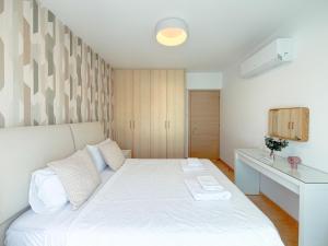a bedroom with a white bed and a desk at Chromata Penthouse Apartment in Paralimni +49 photos