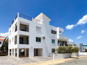 a white apartment building with a blue sky in the background at Chromata Penthouse Apartment in Paralimni