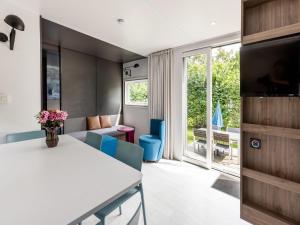 a dining room with a white table and blue chairs at Chalet in Baalse Hei with Modern Comforts in Turnhout +10 photos