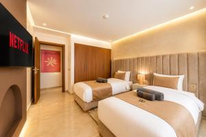 a hotel room with two beds and a television at Kasbel 2 Appart & Pool in Marrakesh +126 photos