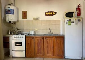 a kitchen with a white refrigerator and a sink at El Cantaro in Villa Elisa