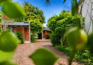 a garden with a brick house with a gravel driveway at El Cantaro in Villa Elisa