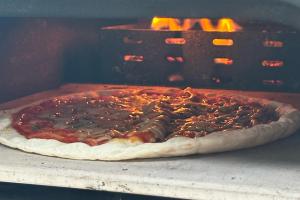 a pizza is being cooked in an oven at 古民家宿 AKIYA cornerstone 淡路島 サウナ ドッグラン in Awaji