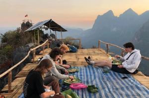 a group of people sitting on a deck eating food at Nongkhiaw Camping 360 c top mountain view in Nongkhiaw