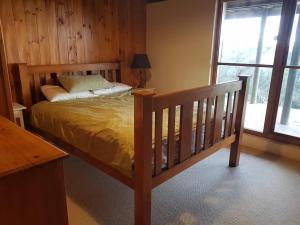 a bedroom with a wooden bed and a window at Possum Ridge in Muston