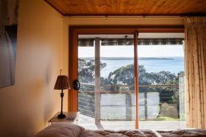 a bedroom with a large window with a view of the ocean at Possum Ridge in Muston