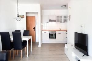 a white kitchen with a dining table and a television at Ferienwohnung auf Fehmarn in Orther Reede in Orth