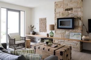 a living room with a stone wall with a tv at The Jetty, Port Willunga in Port Willunga