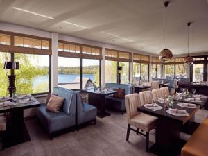 a dining room with tables and chairs and windows at Doppelhaushälfte im Naturresort Drewitz in Drewitz
