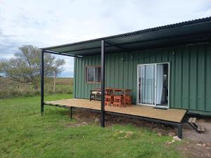 a green house with a wooden deck and a table at Refugio Don Rogelio in Minas