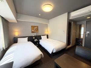 a hotel room with two beds and a table at Hotel Route-Inn Grand Ota Ekimae in Ota
