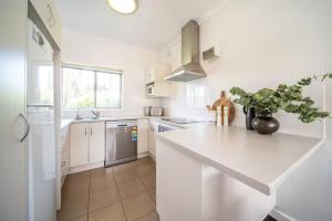 a white kitchen with a large white counter top at Clouds on Francis - Cosy Comfort off Melbourne St in Bowden