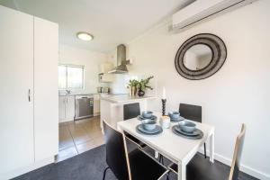 a kitchen and dining room with a white table and chairs at Clouds on Francis - Cosy Comfort off Melbourne St in Bowden +13 photos