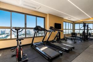 a gym with several tread machines and windows at GRU Residence by Housi in Guarulhos