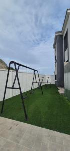 a metal swing set on a lawn next to a house at Renata's Depar in Punta Blanca