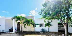a white house with two palm trees in front of it at Casa Mayi Private house with pool in Chablekal in Chablekal