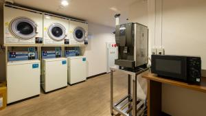a laundry room with washing machines and a tv at Hotel Resh Tottori Ekimae in Tottori