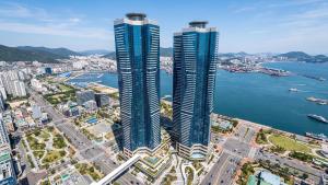 two tall skyscrapers in a city next to the water at Le Collective Busan station in Busan