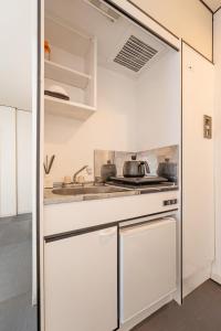 a kitchen with white cabinets and a sink at Namba 5min by subway OYASUMI Manga HOTEL 24 hours Self-check-in Japanese-Style hotel in Osaka
