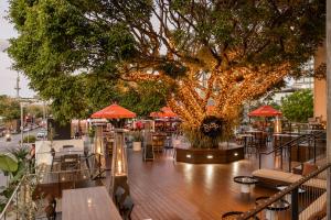 a restaurant with a tree and tables and umbrellas at Rydges Fortitude Valley in Brisbane