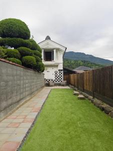 a small white house with a fence and grass at MITSU-House in Nishikatsuracho