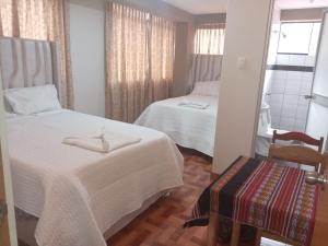 a hotel room with two beds and a chair at Hospedaje San Isidro in Cali