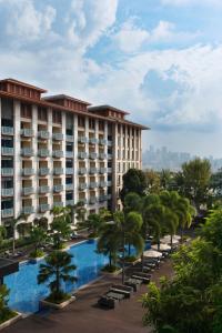 a hotel with a swimming pool and palm trees at Resorts World Sentosa - Hotel Ora in Singapore
